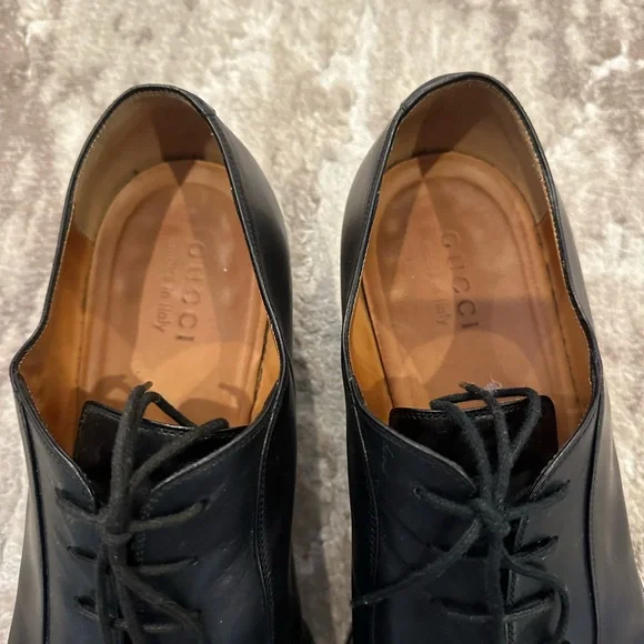 Gucci men’s black dress shoe with gold chain hardware.